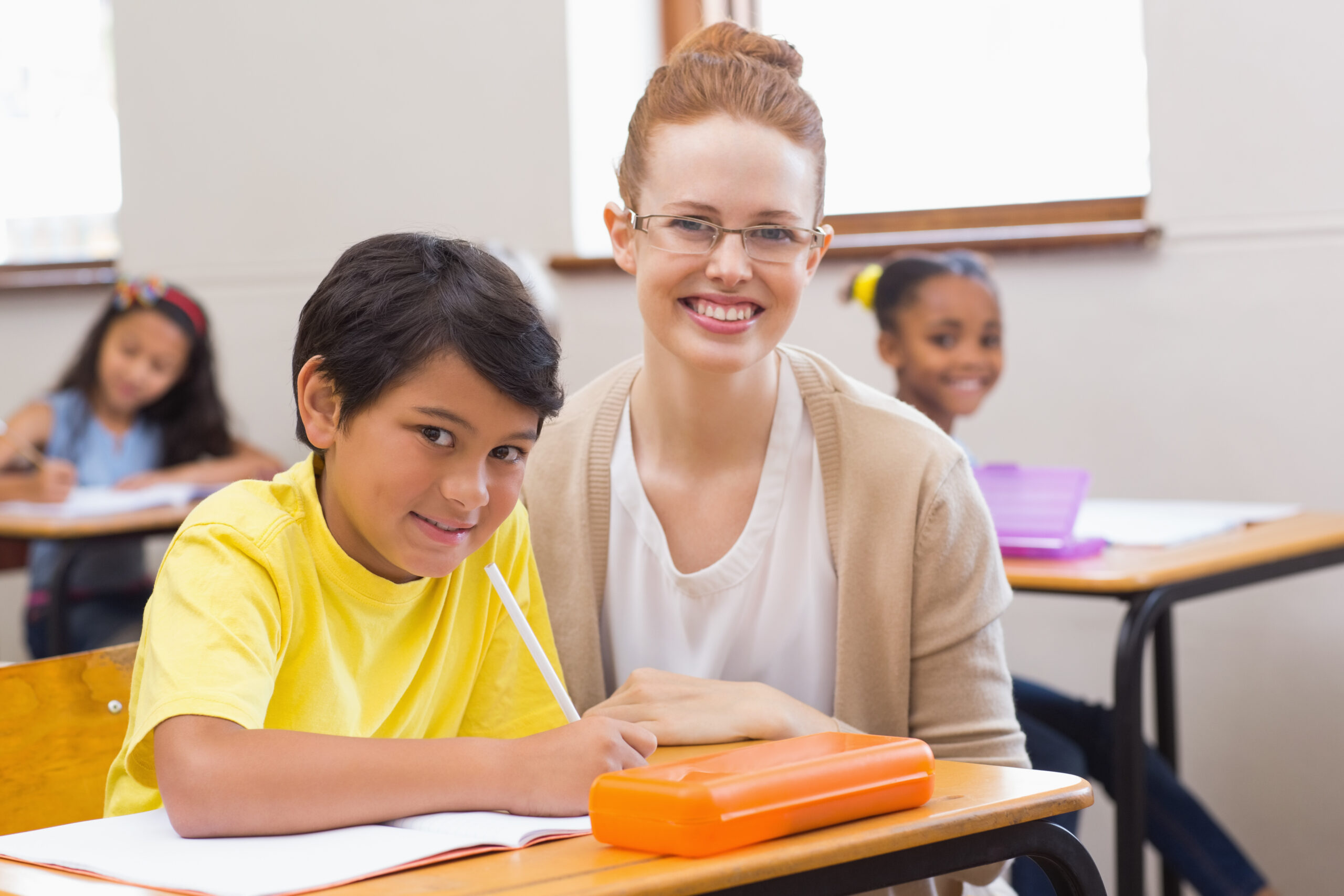 Un'educatrice sta aiutando nei compiti in classe uno studente con bisogni educativi speciali.