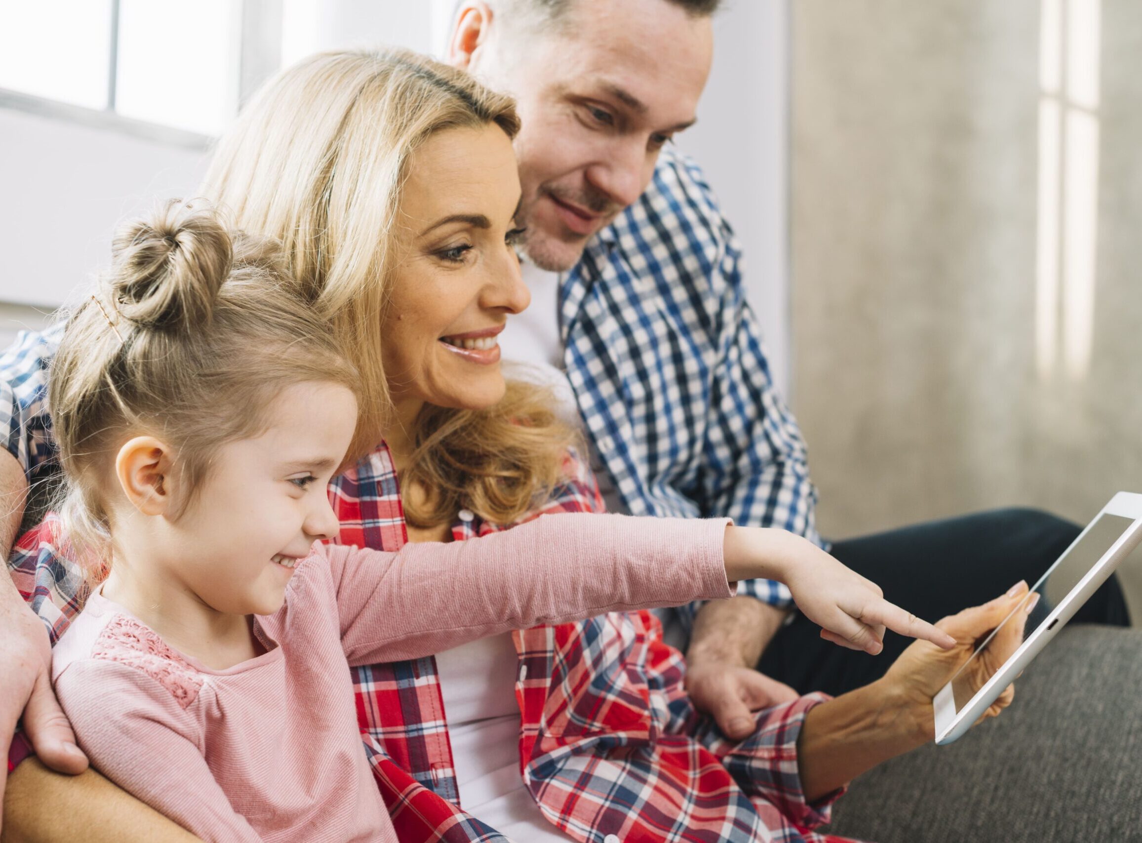Famiglia seduta sul divano guarda assieme il tablet.