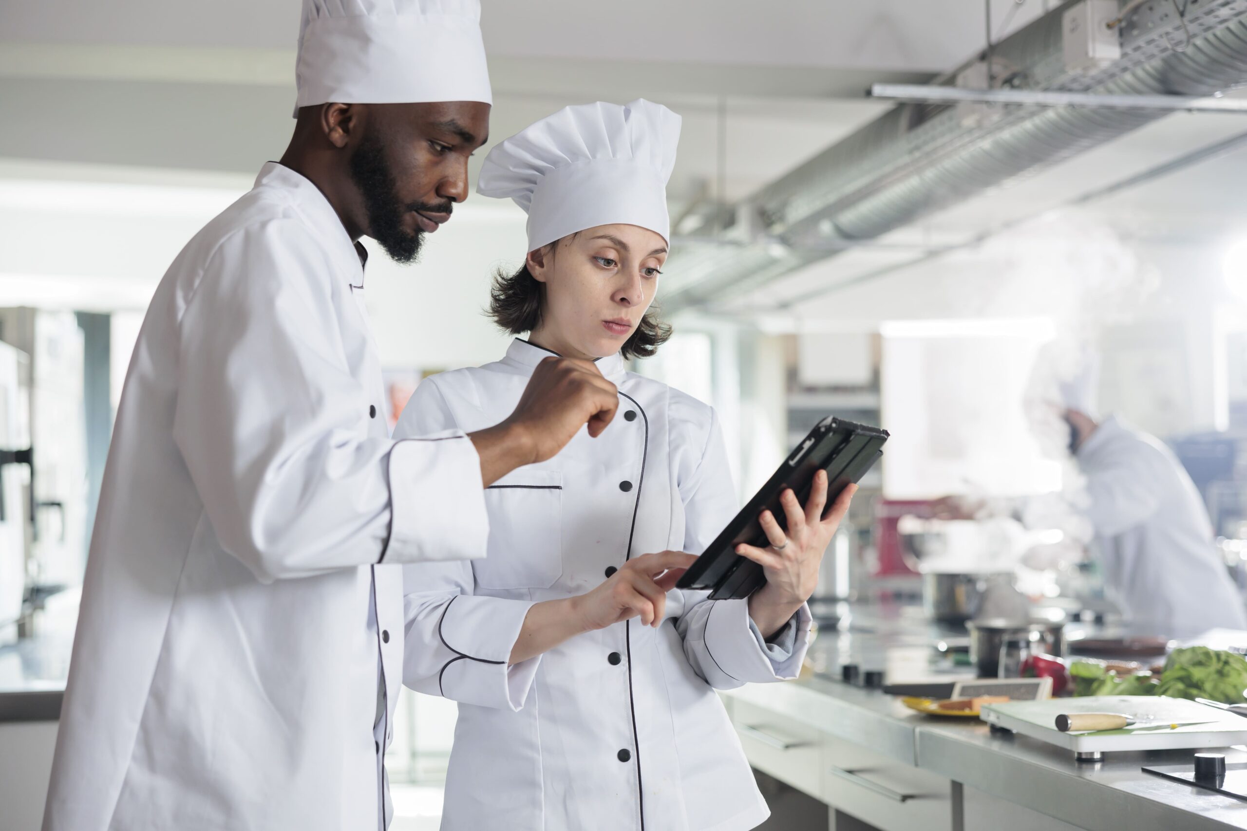 Due cuochi in cucina stanno consultando il tablet.